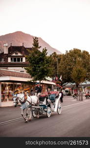 SEP 25, 2013 Interlaken, Switzerland - Evening street scene old vintage Swiss style buildings and horse carriage of Interlaken old town area, famous for tourists.