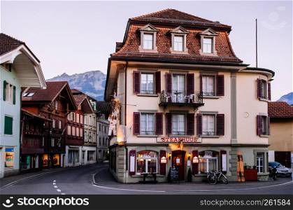 SEP 25, 2013 Interlaken, Switzerland - Evening street scene with car and old vintage Swiss style buildings of Unterseen town and old town area of Interlaken, Switzerland