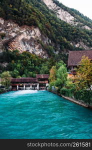 SEP 25, 2013 Interlaken, Switzerland - Turqouise water of Aare river and vintage Swiss style buildings along the shore in old town area with mountain background of Interlaken