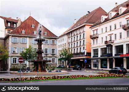 SEP 26, 2013 Neuchatel, Switzerland - Colourful old vintage building of La Chaux de Fonds city and Monumental fountain, the most important centre of the Swiss watch making industry
