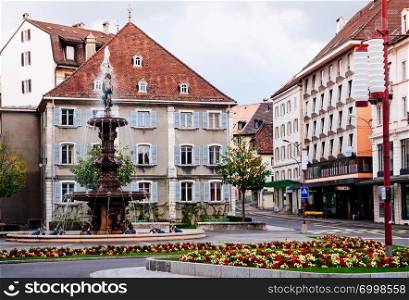 SEP 26, 2013 Neuchatel, Switzerland - Colourful old vintage building of La Chaux de Fonds city and Monumental fountain, the most important centre of the Swiss watch making industry