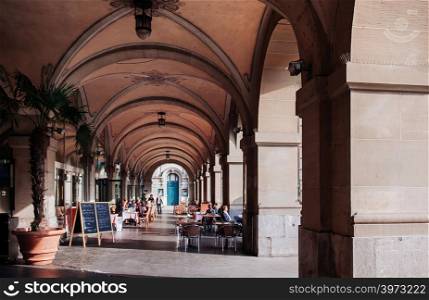 SEP 27, 2013 Bern, Switzerland - European tourists having lunch in street restaurant with dinner table under arch arcade with sunlight in old town Bern.