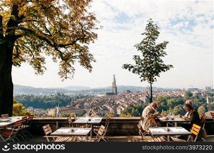SEP 27, 2013 Bern, Switzerland - European tourists sit in restaurant at Rosengarten park with Bern old town scenery and Evangelical Church