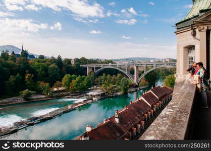 SEP 27, 2013 Bern, Switzerland - Kirchenfeldbrucke bridge over turquoise Aare river and tourist enjoy old town view from Munsterplattform garden of Evangelical church