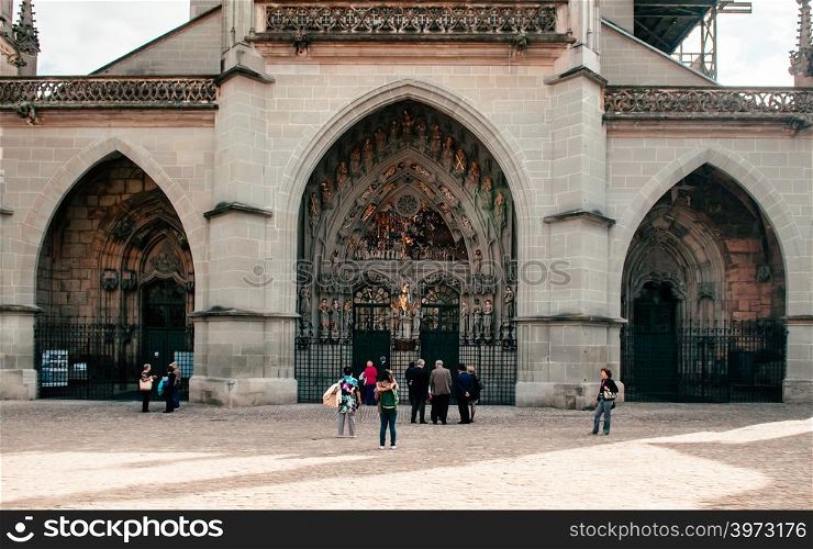 SEP 27, 2013 Bern, Switzerland - Tourist at ArchEntrance gates and front facade of Evangelical Church Burn Munster with Sculptures of the Last Judgement. Gothic style facade sculpture.