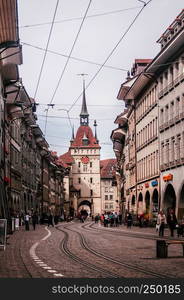 SEP 28, 2013 Bern, Switzerland - Old vintage street scene with tourist walking infront of Kafigturm clock tower. Famous old town area and shopping street