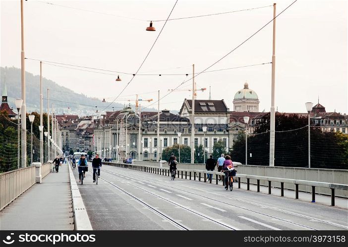 SEP 28, 2013 Bern, Switzerland - Swiss Couple riding bicycle on street of Bern city with old building and green dome of Swiss Parliament in background