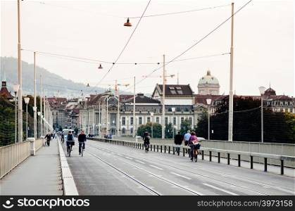 SEP 28, 2013 Bern, Switzerland - Swiss Couple riding bicycle on street of Bern city with old building and green dome of Swiss Parliament in background