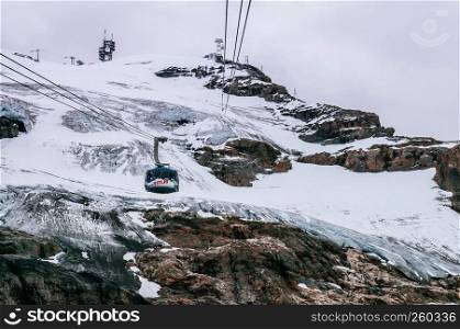 SEp 29, 2013 Engelberg, Switzerland - Rotair cable car ropeway gondola flying over snow covered rocky alpine mountain cliff of Titlis in Engelberg