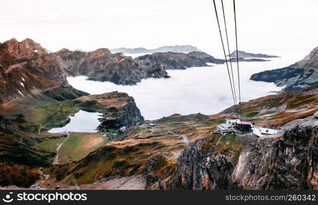 SEp 29, 2013 Engelberg, Switzerland - Stand and Rotair cable car ropeway gondola lift station on edge of cliff over rocky alpine mountain valley and lake Trubsee of Titlis in Engelberg, Switzerland