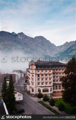 SEP 29, 2013 Engelberg, Switzerland - Swiss classic style chalet on quiet street with Swiss alps of Engelberg town in early autumn on foggy day