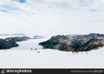 SEP 29, 2013 Engelberg, Switzerland - Tourists walking enjoy wide view of snow slope over cloud and Mountain valley of mount Titlis, famous tourist attraction on Swiss alps.