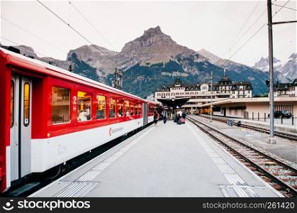 SEP 29, 2013 Engelberg, Switzerland - Tourists with luggages and train at Engelberg station platform with Swiss alps mountain rang in background during autumn season