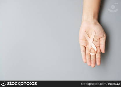 September Uterine Cancer Awareness month, woman hand holding Peach Ribbon for supporting people living and illness. Healthcare and World cancer day concept