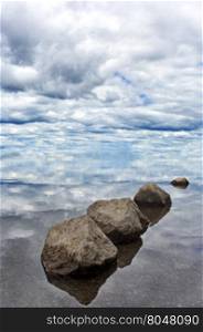 Serene balance of rocks leads gaze to the sky and clouds. Location is Lewis Lake in Yellowstone National Park in Wyoming.