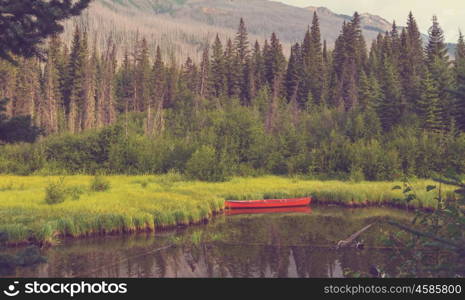 Serene scene by the mountain lake in Canada with reflection of the rocks in the calm water.