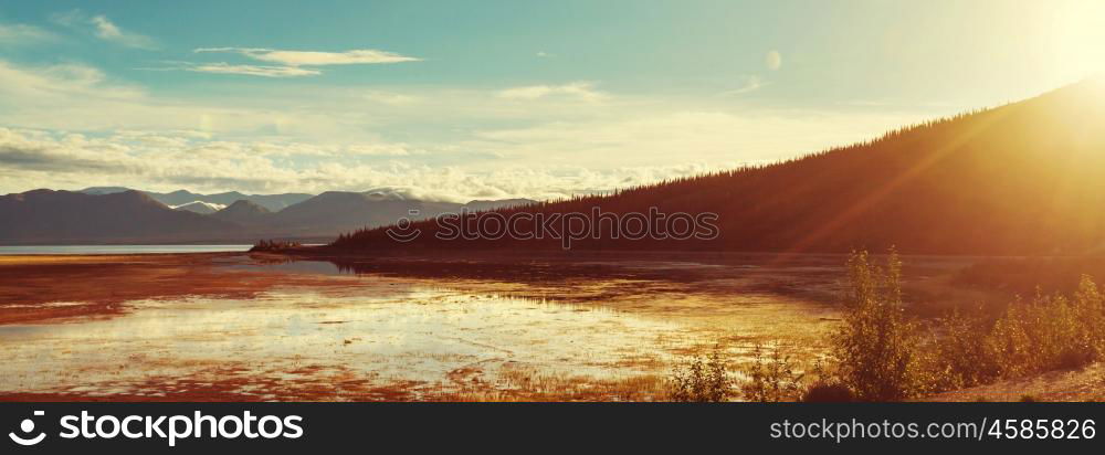 Serene scene by the mountain lake in Canada with reflection of the rocks in the calm water.