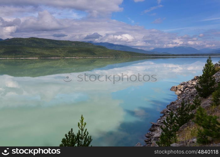 Serene scene by the mountain lake in Canada with reflection of the rocks in the calm water.