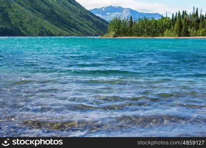 Serene scene by the mountain lake in Canada with reflection of the rocks in the calm water.