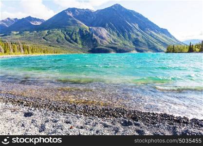 Serene scene by the mountain lake in Canada with reflection of the rocks in the calm water.