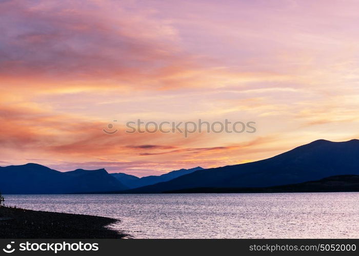 Serene scene by the mountain lake in Canada with reflection of the rocks in the calm water.