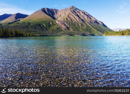 Serene scene by the mountain lake in Canada with reflection of the rocks in the calm water.