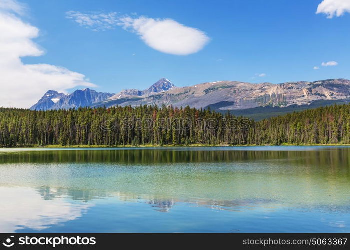 Serene scene by the mountain lake in Canada with reflection of the rocks in the calm water.