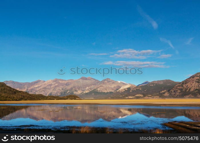 Serene scene by the mountain lake in Canada with reflection of the rocks in the calm water.