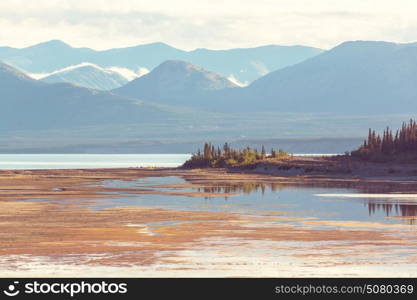 Serene scene by the mountain lake in Canada with reflection of the rocks in the calm water.