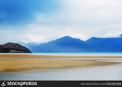 Serene scene by the mountain lake in Canada with reflection of the rocks in the calm water.