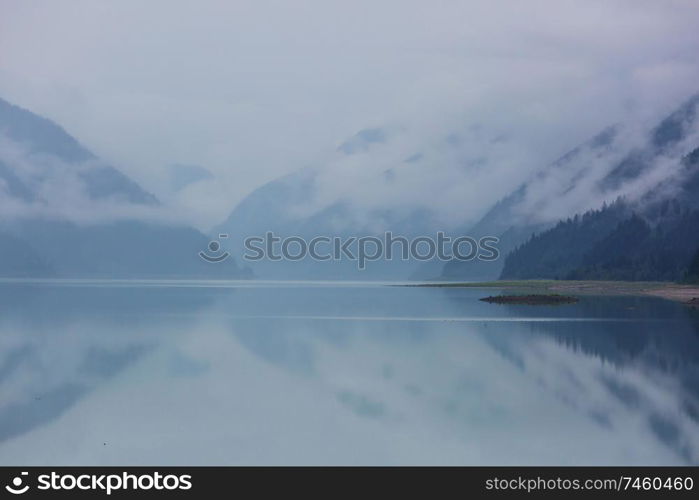 Serene scene by the mountain lake in Canada with reflection of the rocks in the calm water.