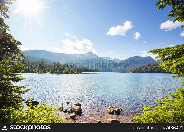 Serene scene by the mountain lake in Canada with reflection of the rocks in the calm water.
