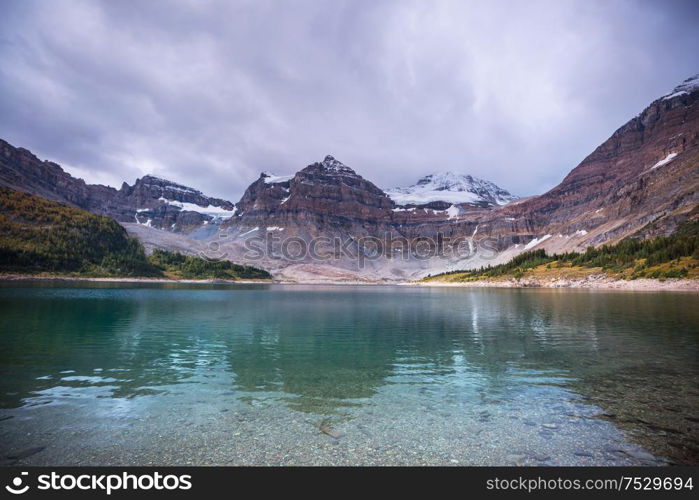 Serene scene by the mountain lake in Canada with reflection of the rocks in the calm water.