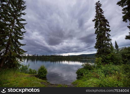 Serene scene by the mountain lake in Canada with reflection of the rocks in the calm water.