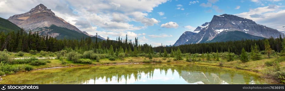 Serene scene by the mountain lake in Canada with reflection of the rocks in the calm water.