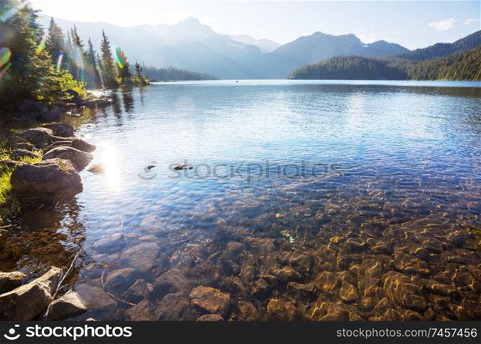 Serene scene by the mountain lake with reflection of the rocks in the calm water.
