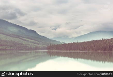 Serene scene by the mountain lake with reflection of the rocks in the calm water.