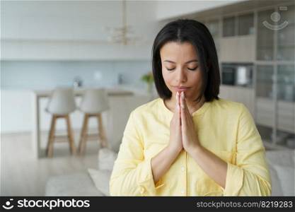 Serene young woman practice yoga, meditating, breathing folded hands in namaste gesture at home. Calm female praying with closed eyes. Healthy lifestyle, meditation, stress relief concept.. Female meditating or praying with namaste gesture at home. Healthy lifestyle, stress relief