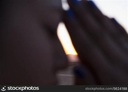 Serene young woman with eyes closed and hands together in prayer pose in the desert in China, side view, extreme close up