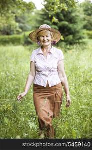 Serenity. Friendly Senior Peasant Woman in Straw in Meadow Smiling
