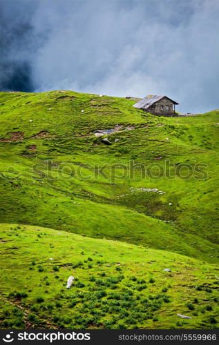 Serenity serene lonely scenery background concept - house in hills in mountins on alpine meadow in clouds