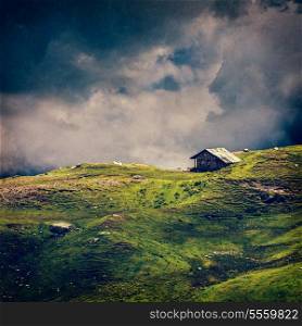 Serenity serene lonely scenery background concept - old house in hills in mountins on alpine meadow in clouds. VIntage style cross process, grain and texture added