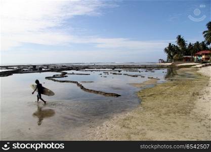 Serfer walking on the Pantai Sorake beach in Nias island, Indonesia