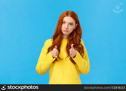 Serious and determined supportive redhead girlfriend, showing you can do it, encourage friend, make thumbs-up in approval, rooting for you, glance with confident expression, blue background.. Serious and determined supportive redhead girlfriend, showing you can do it, encourage friend, make thumbs-up in approval, rooting for you, glance with confident expression, blue background