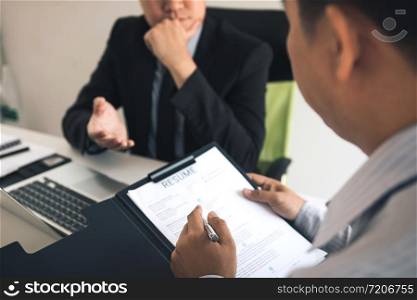 Serious asian businessman important conversation with male employee are reviewing resume documents.