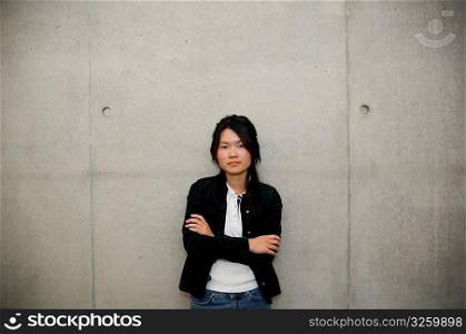 Serious Asian girl against cement wall.