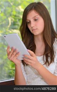 Serious attractive young girl reading information on a tablet computer