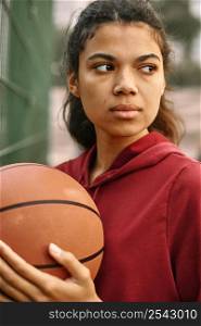 serious black american woman playing basketball