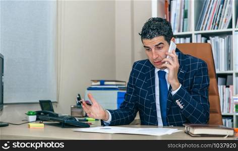 Serious businessman having a discussion by phone sitting in the office. Businessman having discussion by phone in office