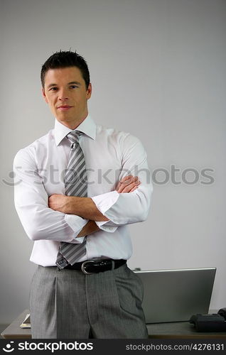 Serious businessman man by his desk arms folded